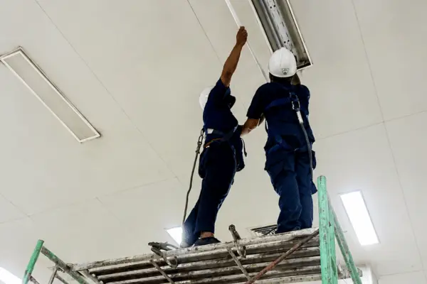 teknisi melakukan pemasangan lampu gedung